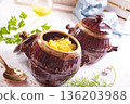 Corn porridge in a clay plate, a clay pot with porridge on a light background 136203988