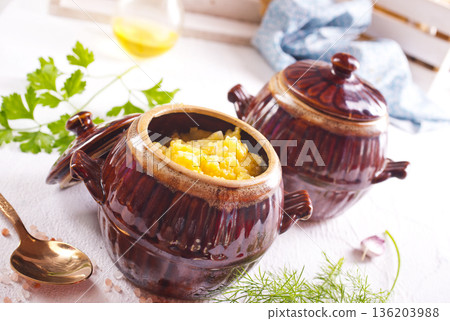 Corn porridge in a clay plate, a clay pot with porridge on a light background Corn porridge in a clay plate, a clay pot with porridge on a light background 136203988
