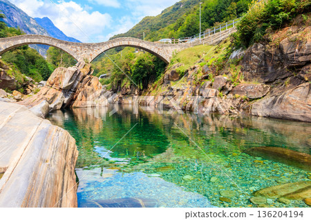 Ancient double arch stone Roman bridge (Ponte dei Salti) over the clear water of the Verzasca river in Lavertezzo ,Verzasca Valley, Ticino Canton, Switzerland Ancient double arch stone Roman bridge (Ponte dei Salti) over the clear water of the Verzasca river in Lavertezzo ,Verzasca Valley, Ticino Canton, Switzerland 136204194