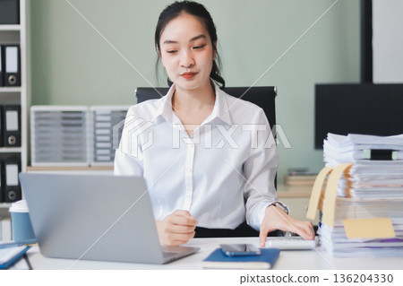 Charming smiling adult woman middle aged woman with curly hair architect designer working on computer in the bright modern office Charming smiling adult woman middle aged woman with curly hair architect designer working on computer in the bright modern office 136204330