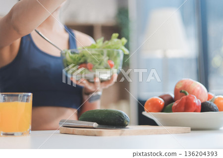 Fit young Asian women in activewear sitting on yoga mat and eating fresh vegetable salad after workout, representing clean eating, fitness lifestyle, wellness routine and health balance. Fit young Asian women in activewear sitting on yoga mat and eating fresh vegetable salad after workout, representing clean eating, fitness lifestyle, wellness routine and health balance. 136204393