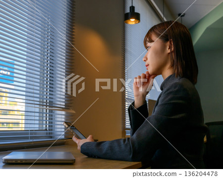 女子在窗邊看著智慧型手機 136204478