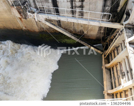 Powerful water discharge through the dam gate. 136204496