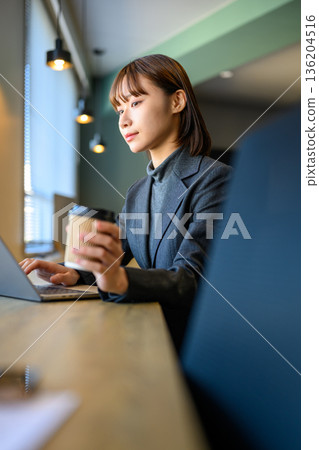 一位女士在咖啡館使用電腦。 136204516