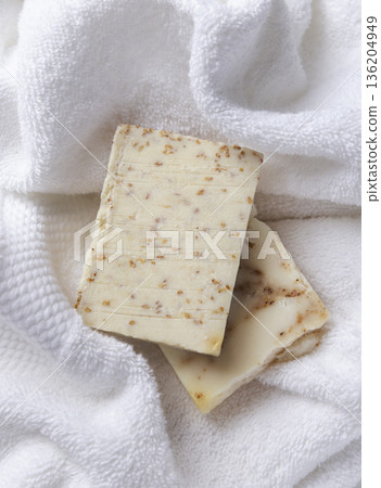 Unbranded beige solid soap bars on white terry towel top view, bathroom spa amenities 136204949