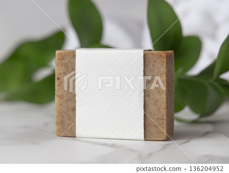 Mockup of brown solid soap bar with paper label and green leaves near white bath towels, personal care Mockup of brown solid soap bar with paper label and green leaves near white bath towels, personal care 136204952