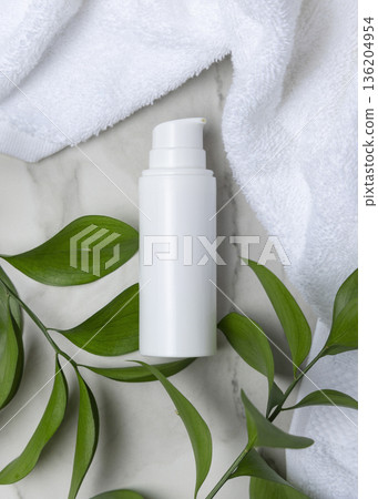 Mockup of blank white pump bottle near white bath terry towel and green leaves. Unbranded cosmetic 136204954