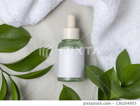 Glass dropper bottle near white bath towel and green leaves top view, skincare packaging mockup Glass dropper bottle near white bath towel and green leaves top view, skincare packaging mockup 136204955