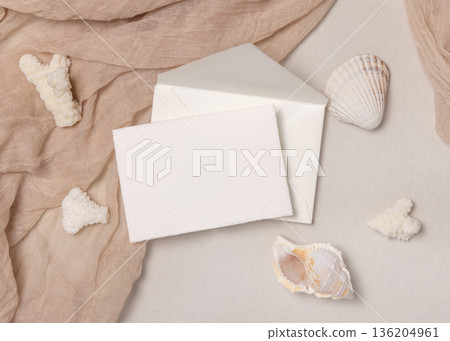 Mockup of blank card on envelope near seashells and coral on stone. Beach party stationery Mockup of blank card on envelope near seashells and coral on stone. Beach party stationery 136204961
