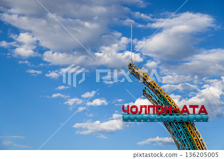 Bright cheerful welcoming sign to Cholpon-Ata town on Issyk-Kul lake with red letters and blue border outdoors 136205005