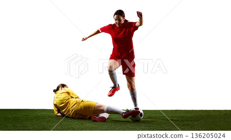 Female soccer player jumping over sliding tackle on field. Female soccer player jumping over sliding tackle on field. 136205024