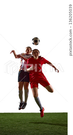 Female soccer players jumping to contest ball in aerial duel. 136205039