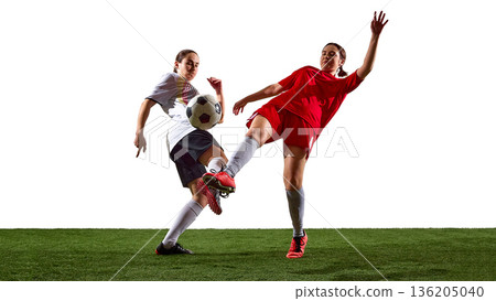 Female soccer players competing for ball during mid air kick. 136205040