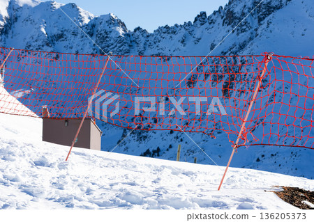 Snowy mountain landscape with red safety net in alpine setting 136205373