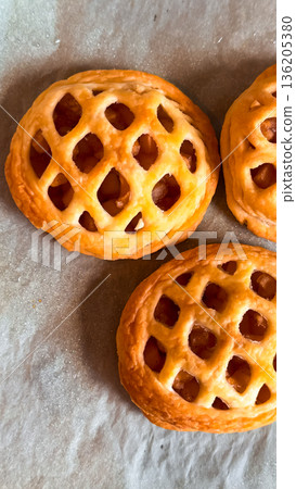 Golden brown apple hand pies with lattice crust on baking sheet 136205380