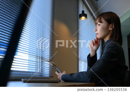 Woman looking at smartphone by the window 136205536