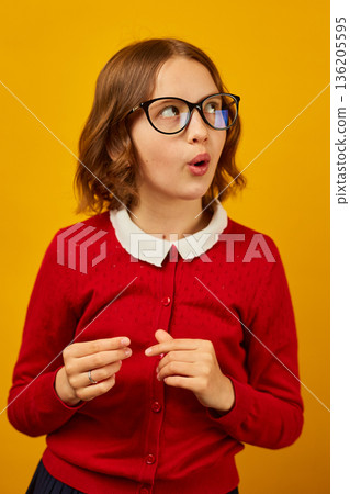 Girl with glasses smiles brightly in front of a yellow background while posing for the camera during a casual afternoon 136205595