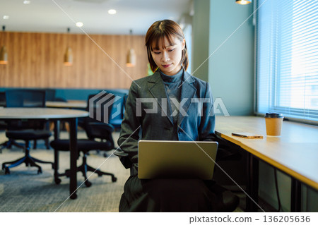 Woman working on a laptop in the office Woman working on a laptop in the office 136205636
