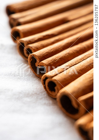 Cinnamon cassia sticks stacked together, showcasing their rich brown color and curled ends. Ideal for culinary and aromatic uses. 136205787