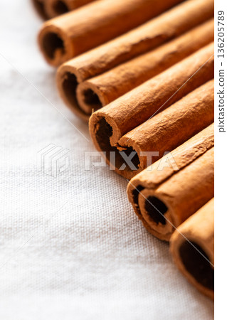 Cinnamon cassia sticks stacked together, showcasing their rich brown color and curled ends. Ideal for culinary and aromatic uses. 136205789