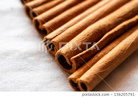 Cinnamon cassia sticks stacked together, showcasing their rich brown color and curled ends. Ideal for culinary and aromatic uses. 136205791