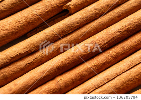 Cinnamon cassia sticks stacked together, showcasing their rich brown color and curled ends. Ideal for culinary and aromatic uses. 136205794