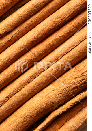 Cinnamon cassia sticks stacked together, showcasing their rich brown color and curled ends. Ideal for culinary and aromatic uses. 136205799