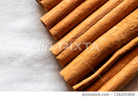 Cinnamon cassia sticks stacked together, showcasing their rich brown color and curled ends. Ideal for culinary and aromatic uses. 136205800