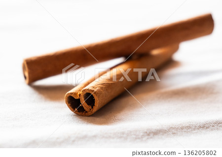 Cinnamon cassia sticks stacked together, showcasing their rich brown color and curled ends. Ideal for culinary and aromatic uses. 136205802