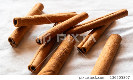 Cinnamon cassia sticks stacked together, showcasing their rich brown color and curled ends. Ideal for culinary and aromatic uses. 136205807