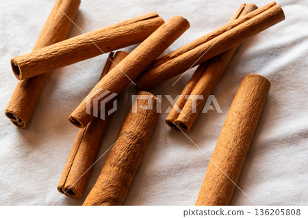 Cinnamon cassia sticks stacked together, showcasing their rich brown color and curled ends. Ideal for culinary and aromatic uses. 136205808