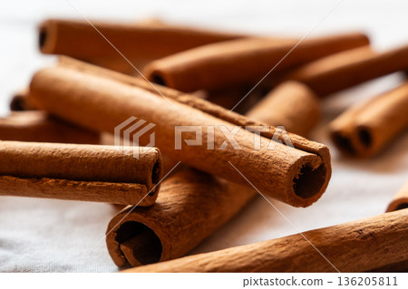 Cinnamon cassia sticks stacked together, showcasing their rich brown color and curled ends. Ideal for culinary and aromatic uses. 136205811