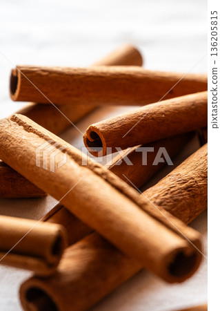 Cinnamon cassia sticks stacked together, showcasing their rich brown color and curled ends. Ideal for culinary and aromatic uses. 136205815