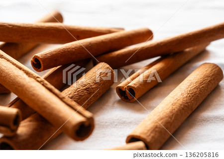 Cinnamon cassia sticks stacked together, showcasing their rich brown color and curled ends. Ideal for culinary and aromatic uses. 136205816