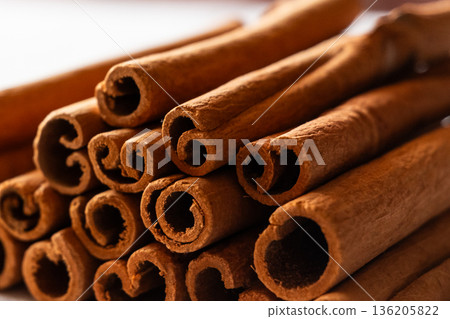 Cinnamon cassia sticks stacked together, showcasing their rich brown color and curled ends. Ideal for culinary and aromatic uses. 136205822