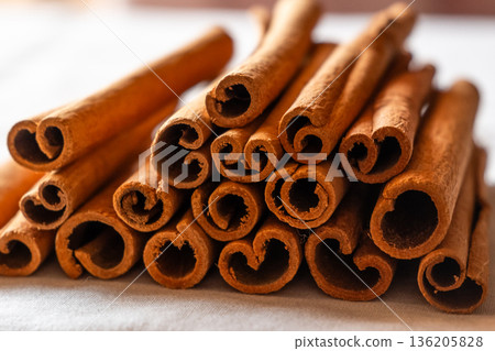 Cinnamon cassia sticks stacked together, showcasing their rich brown color and curled ends. Ideal for culinary and aromatic uses. 136205828