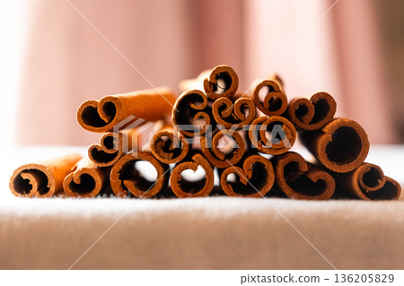 Cinnamon cassia sticks stacked together, showcasing their rich brown color and curled ends. Ideal for culinary and aromatic uses. 136205829