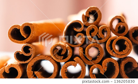 Cinnamon cassia sticks stacked together, showcasing their rich brown color and curled ends. Ideal for culinary and aromatic uses. 136205830