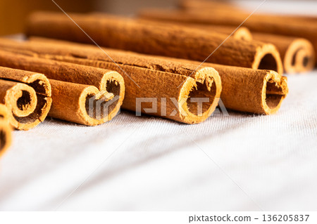 Cinnamon cassia sticks stacked together, showcasing their rich brown color and curled ends. Ideal for culinary and aromatic uses. 136205837