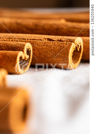 Cinnamon cassia sticks stacked together, showcasing their rich brown color and curled ends. Ideal for culinary and aromatic uses. 136205840