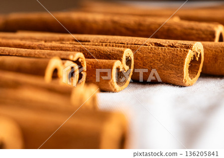 Cinnamon cassia sticks stacked together, showcasing their rich brown color and curled ends. Ideal for culinary and aromatic uses. Cinnamon cassia sticks stacked together, showcasing their rich brown color and curled ends. Ideal for culinary and aromatic uses. 136205841