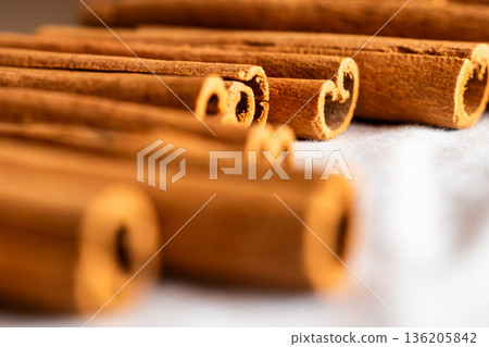Cinnamon cassia sticks stacked together, showcasing their rich brown color and curled ends. Ideal for culinary and aromatic uses. 136205842