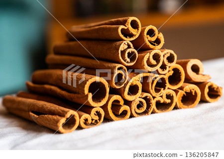 Cinnamon cassia sticks stacked together, showcasing their rich brown color and curled ends. Ideal for culinary and aromatic uses. 136205847