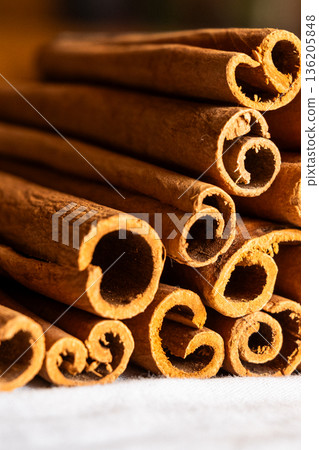 Cinnamon cassia sticks stacked together, showcasing their rich brown color and curled ends. Ideal for culinary and aromatic uses. 136205848