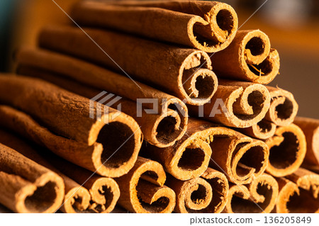 Cinnamon cassia sticks stacked together, showcasing their rich brown color and curled ends. Ideal for culinary and aromatic uses. 136205849