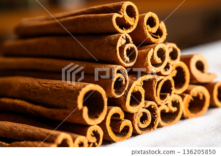 Cinnamon cassia sticks stacked together, showcasing their rich brown color and curled ends. Ideal for culinary and aromatic uses. 136205850