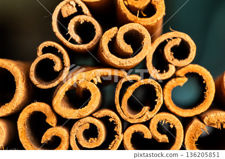 Cinnamon cassia sticks stacked together, showcasing their rich brown color and curled ends. Ideal for culinary and aromatic uses. 136205851