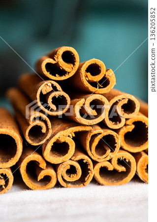 Cinnamon cassia sticks stacked together, showcasing their rich brown color and curled ends. Ideal for culinary and aromatic uses. 136205852