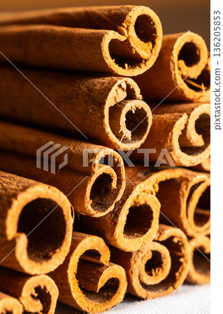 Cinnamon cassia sticks stacked together, showcasing their rich brown color and curled ends. Ideal for culinary and aromatic uses. 136205853