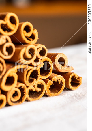 Cinnamon cassia sticks stacked together, showcasing their rich brown color and curled ends. Ideal for culinary and aromatic uses. 136205856